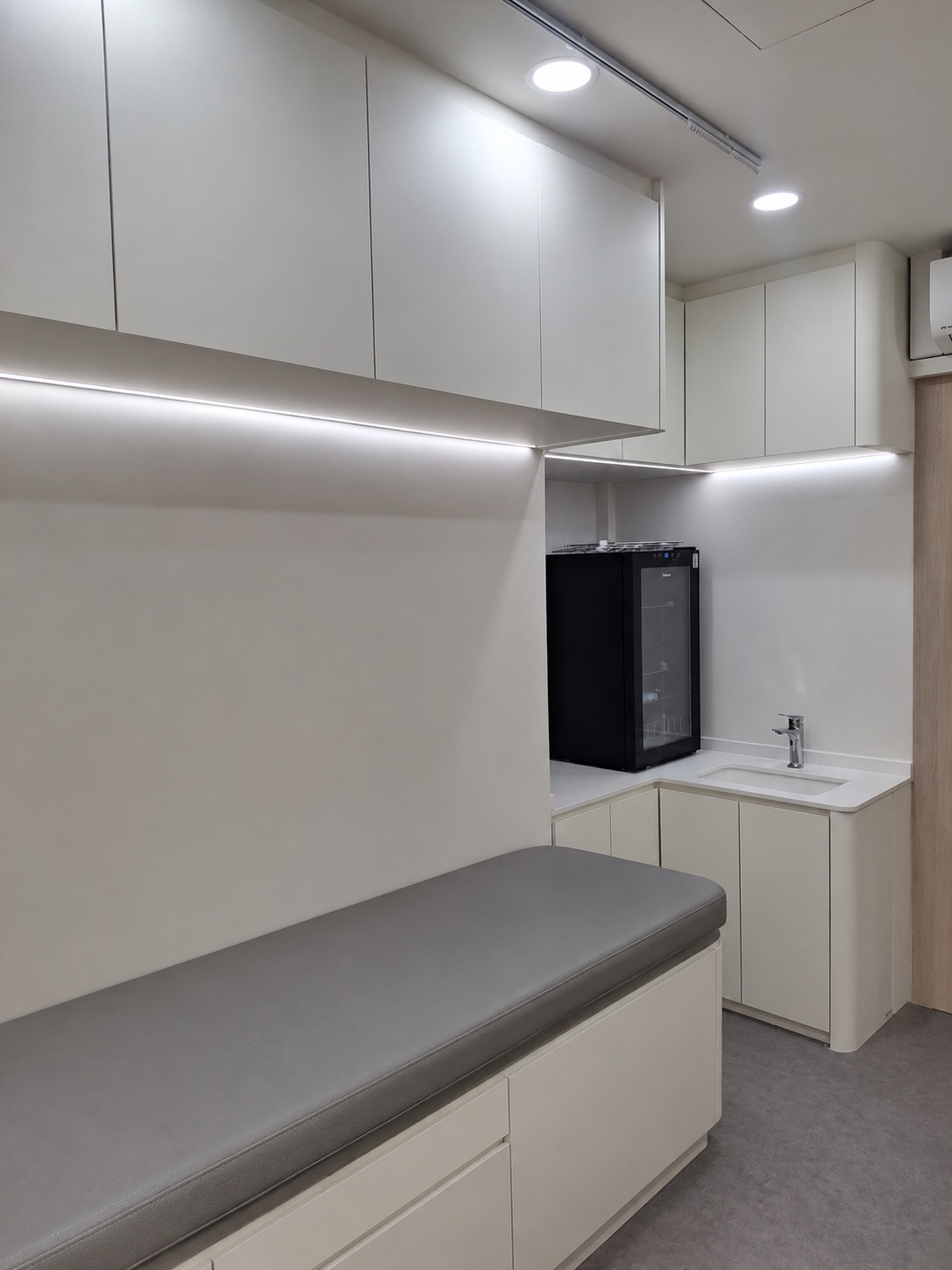 Clinic consultation and treatment room with handwash basin, storage and exam bench