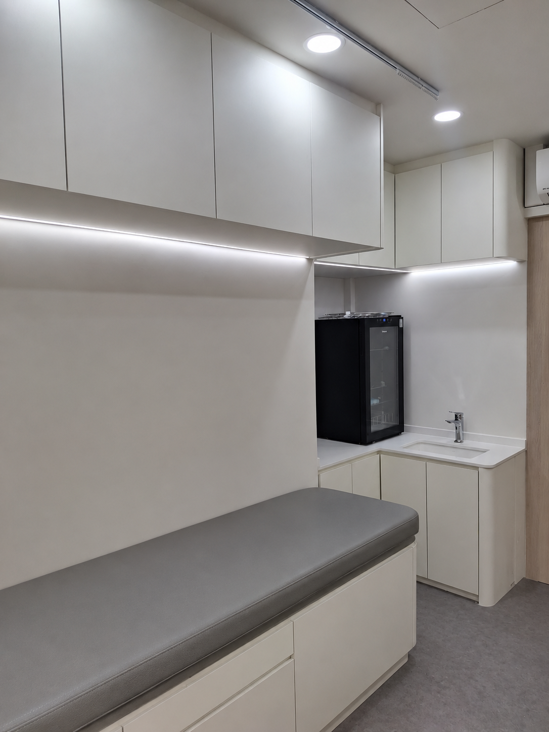 Clinic consultation and treatment room with handwash basin, storage and exam bench