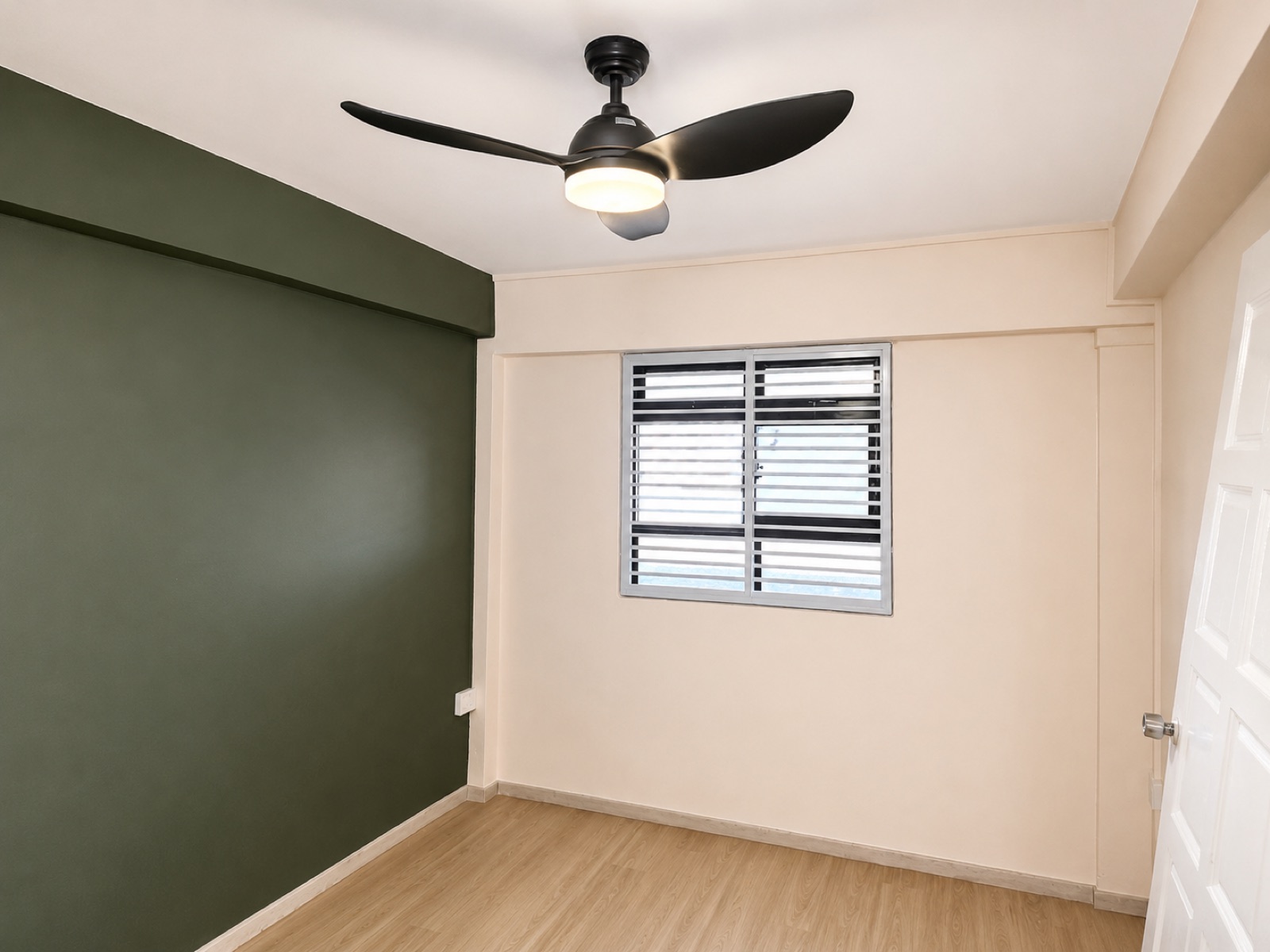 Finished HDB bedroom with a forest-green accent wall, blush walls, ceiling fan and wood-laminate flooring